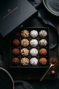 Assorted homemade chocolate truffles dusted in cocoa powder arranged on a dark slate board